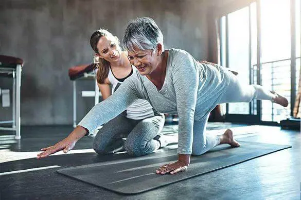 Physical therapist helping an elderly woman do her exercise regimen.