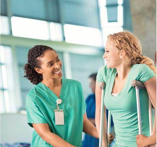 Female patient on a walker and a physical therapist happily doing their exercise routine.