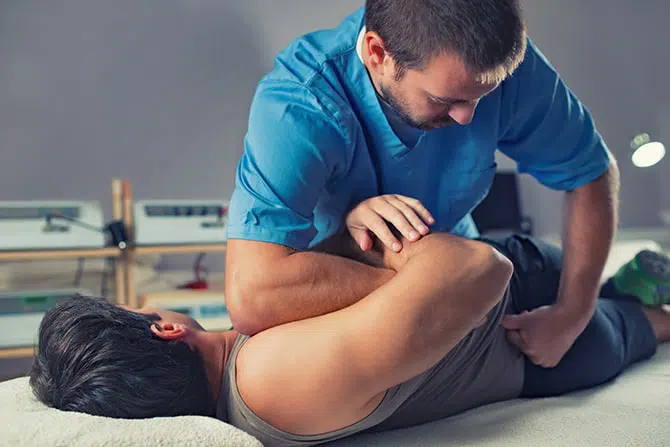 Chiropractor adjusting a male patient's back.
