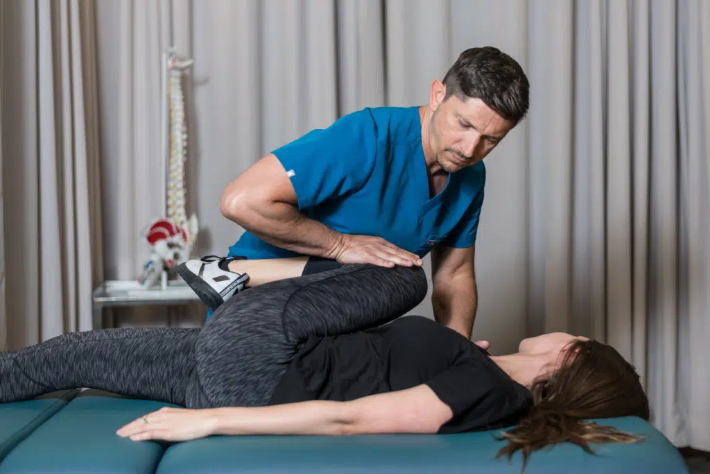Male chiropractor in the Woodlands providing chiropractic care to a female patient lying down on her back
