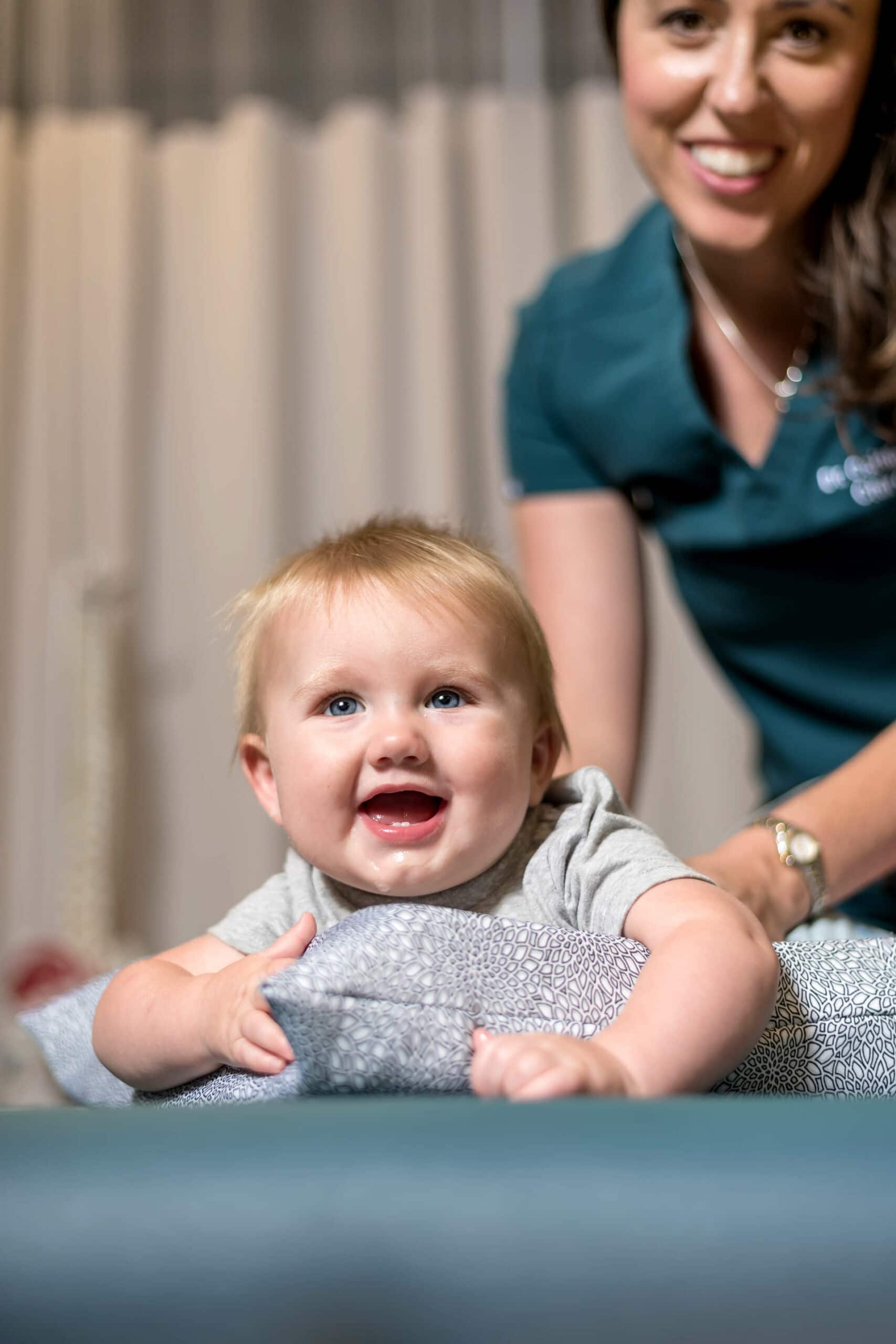 smiling toddler with a female chiropractor smiling at the back