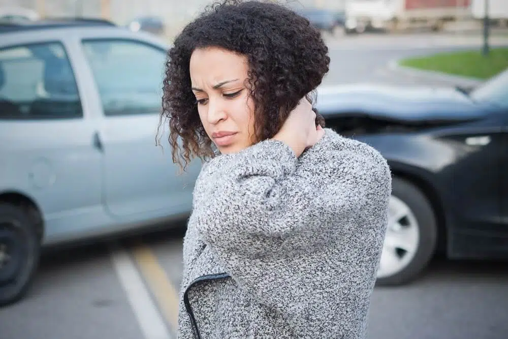 Woman's neck in pain from car crash in the background