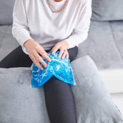 injured woman treating her knee with an ice pack