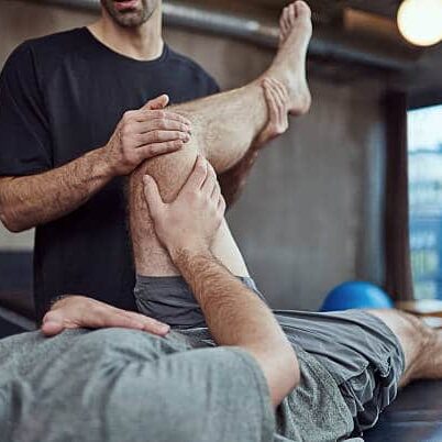 Chiropractor is treating a patient that suffers from sports injury on his knee