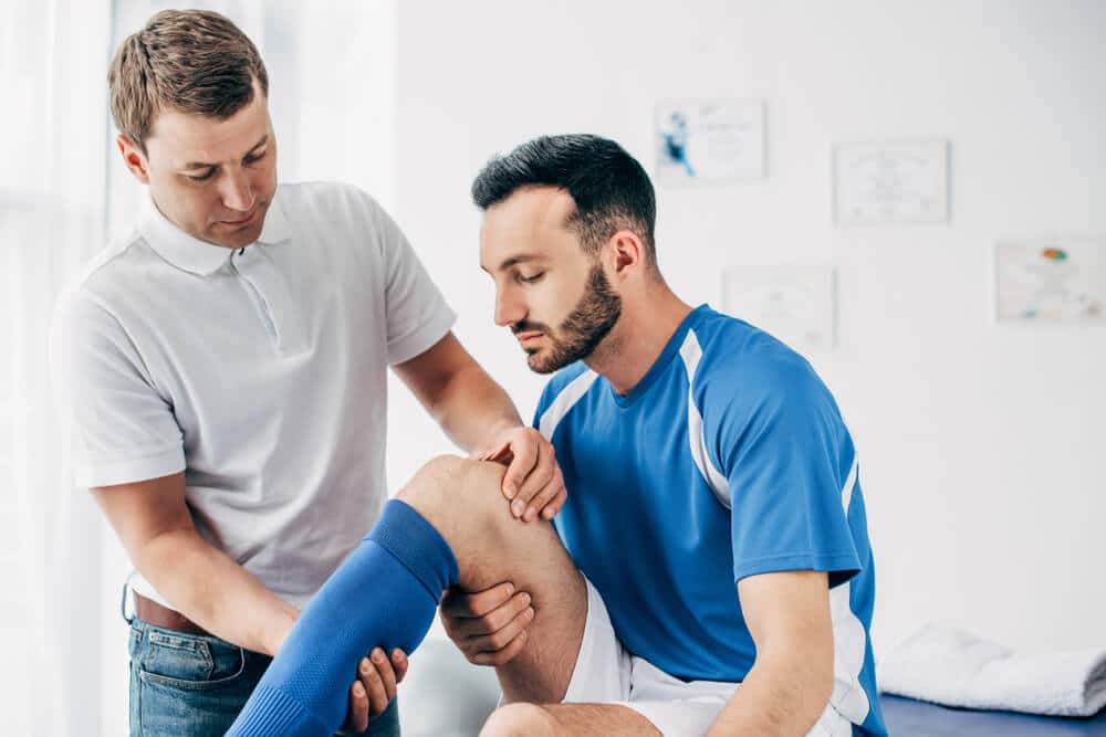 chiropractor examining an athlete's injured knee