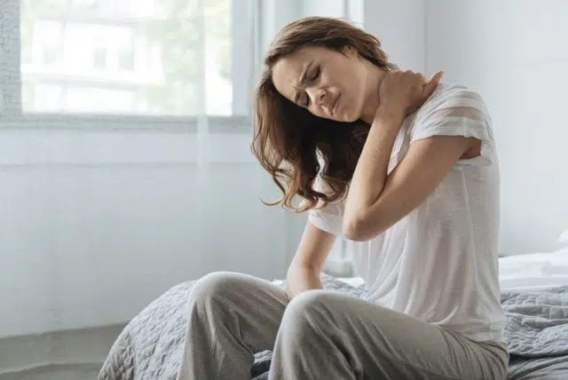 Young woman holding her neck  because of stiff neck 