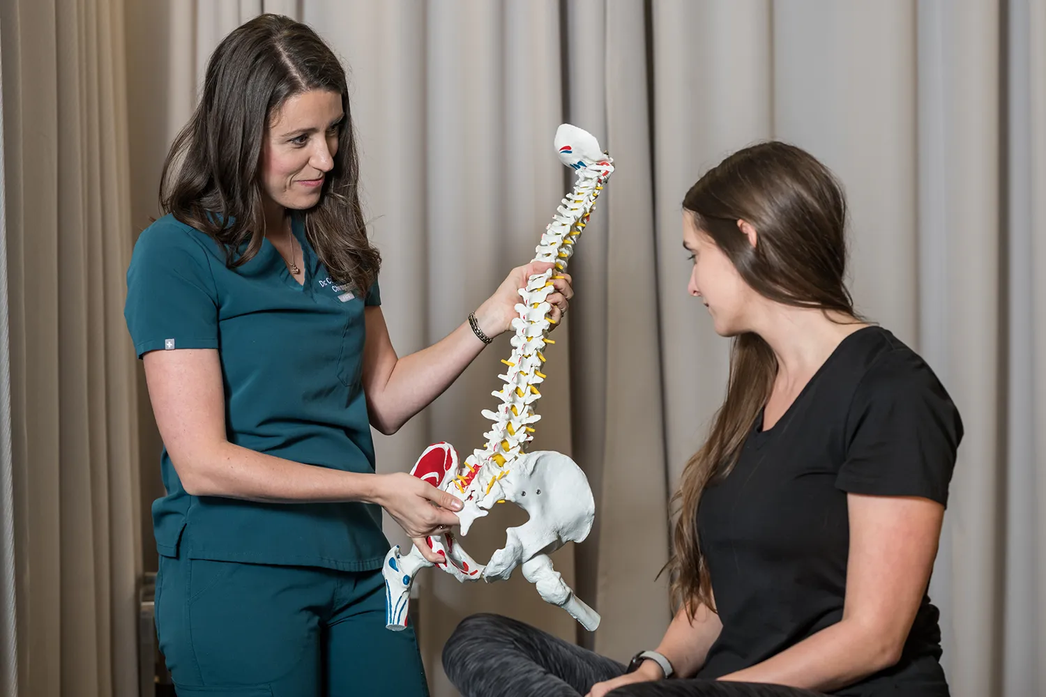 Chiropractor showing a model of a spine to a patient
