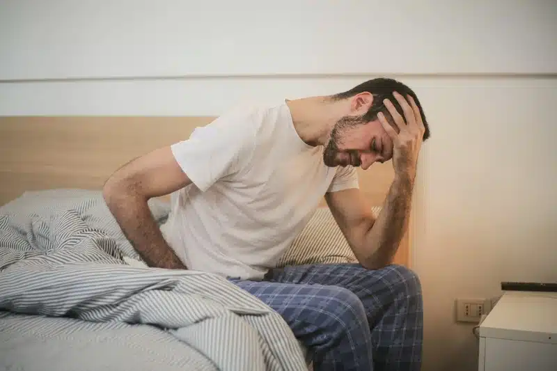 Man sitting on his bed suffer from Fibromyalgia due to fatigue 