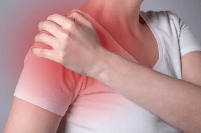 Woman holding her shoulder feeling of too much pain.