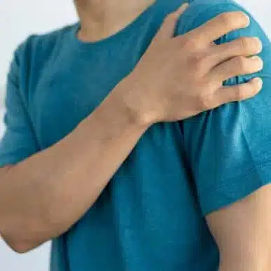 Close-up of a man with pain in his shoulder caused by sprain.