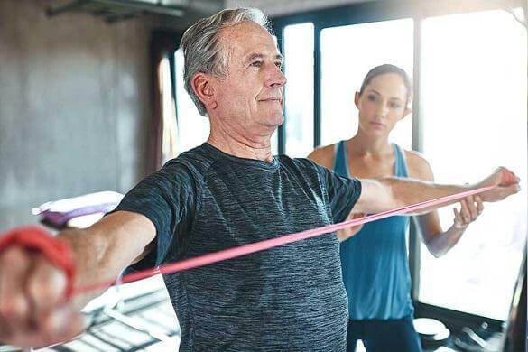Physiotherapist helping a senior man to under go a physical therapy.