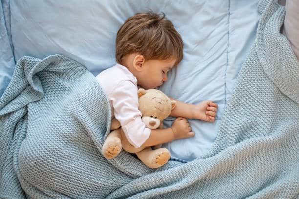 Photo of baby boy sleeping together with teddy bear.