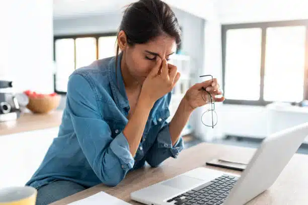 Woman suffers from headache and migraine after sitting in her office chair for a day at work.