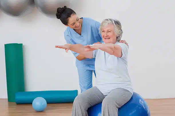 Physiotherapist helping a senior patient to to some stretching and exercise.