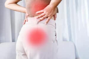 Woman holding her lower back and leg from sciatic nerve pain