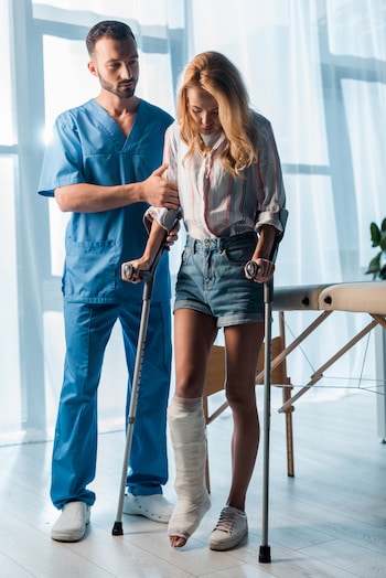 therapist helping woman on walker for personal injury treatment