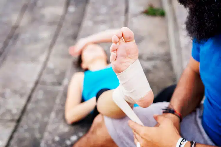 man wrapping the foot of a woman who injured herself