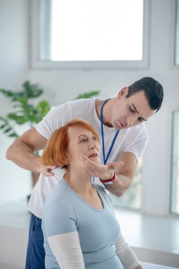 skilled chiropractor doing assessment on female patient with personal injury