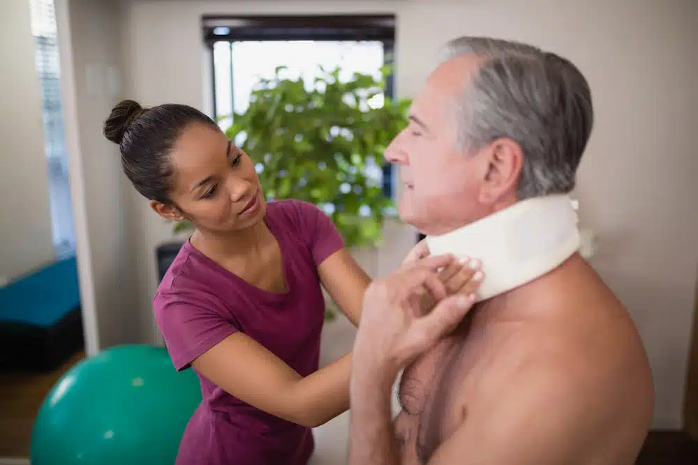 female chiropractor removing neck support of a  patient with whiplash before rehabilitation session