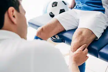chiropractor examining athlete's knee after a sport injury