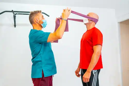 patient doing neck exercises with chiropractor during physical Rehabilitation for whiplash 