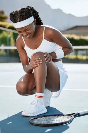 tennis player with injury holding her knee from pain