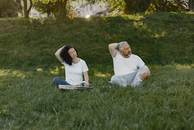 elderly copule sitting in the park doing neck exercises