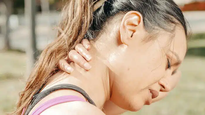 athlete with text neck pain holding her neck