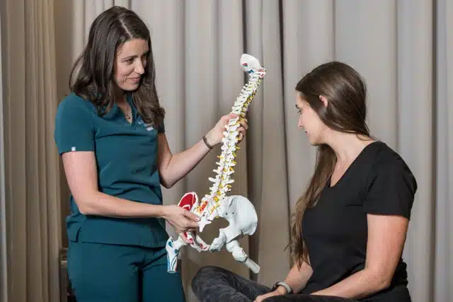 chiropractor showing a skeletal spine model