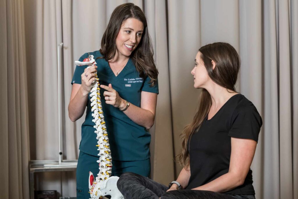 Chiropractor using a spine model to educate a patient during a consultation.