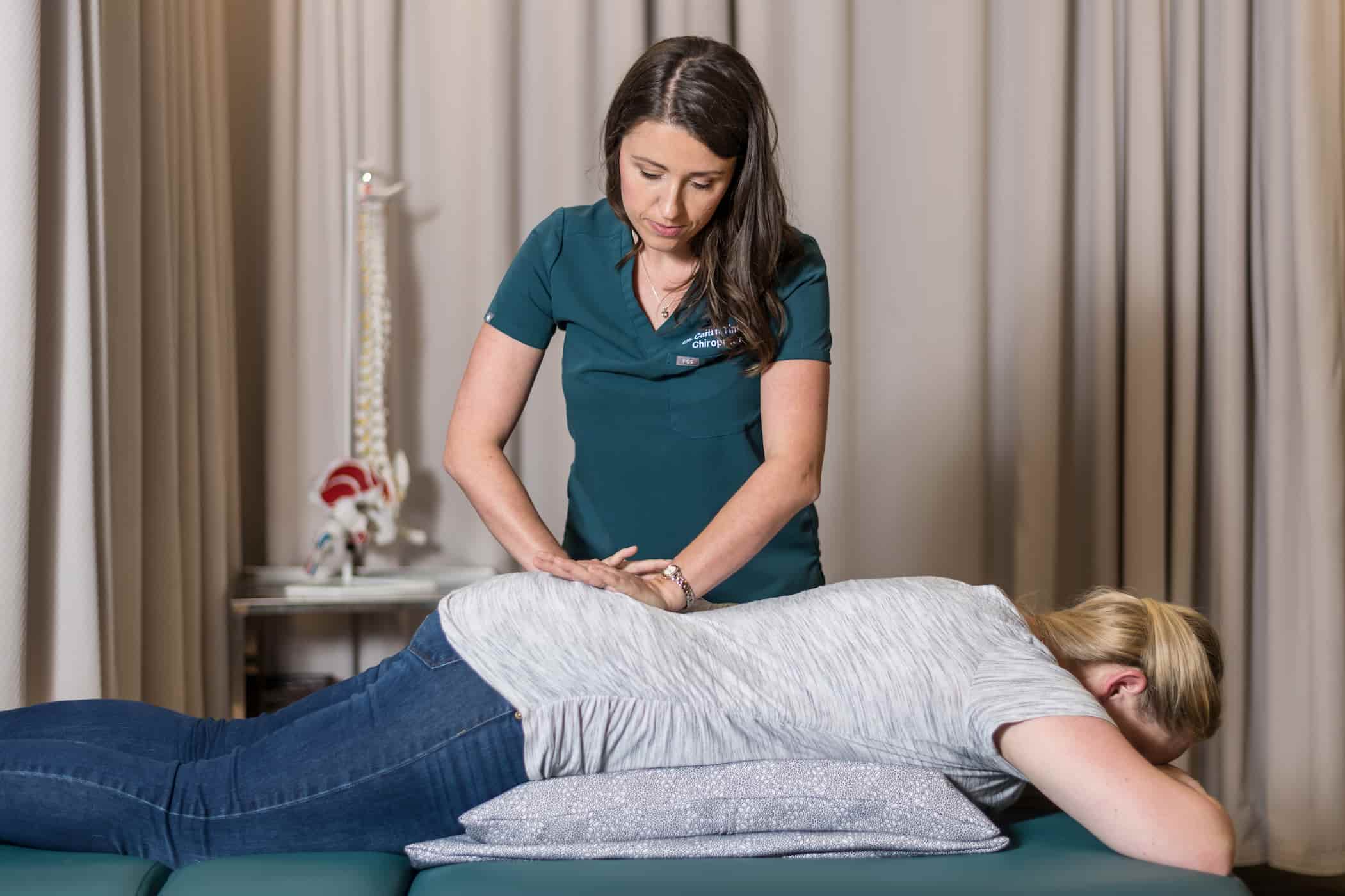 Chiropractor preparing to perform a lumbar spinal adjustment on a patient.