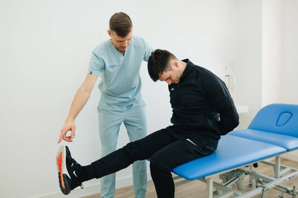 Sports medicine specialist guiding athlete through functional leg rehabilitation exercise.