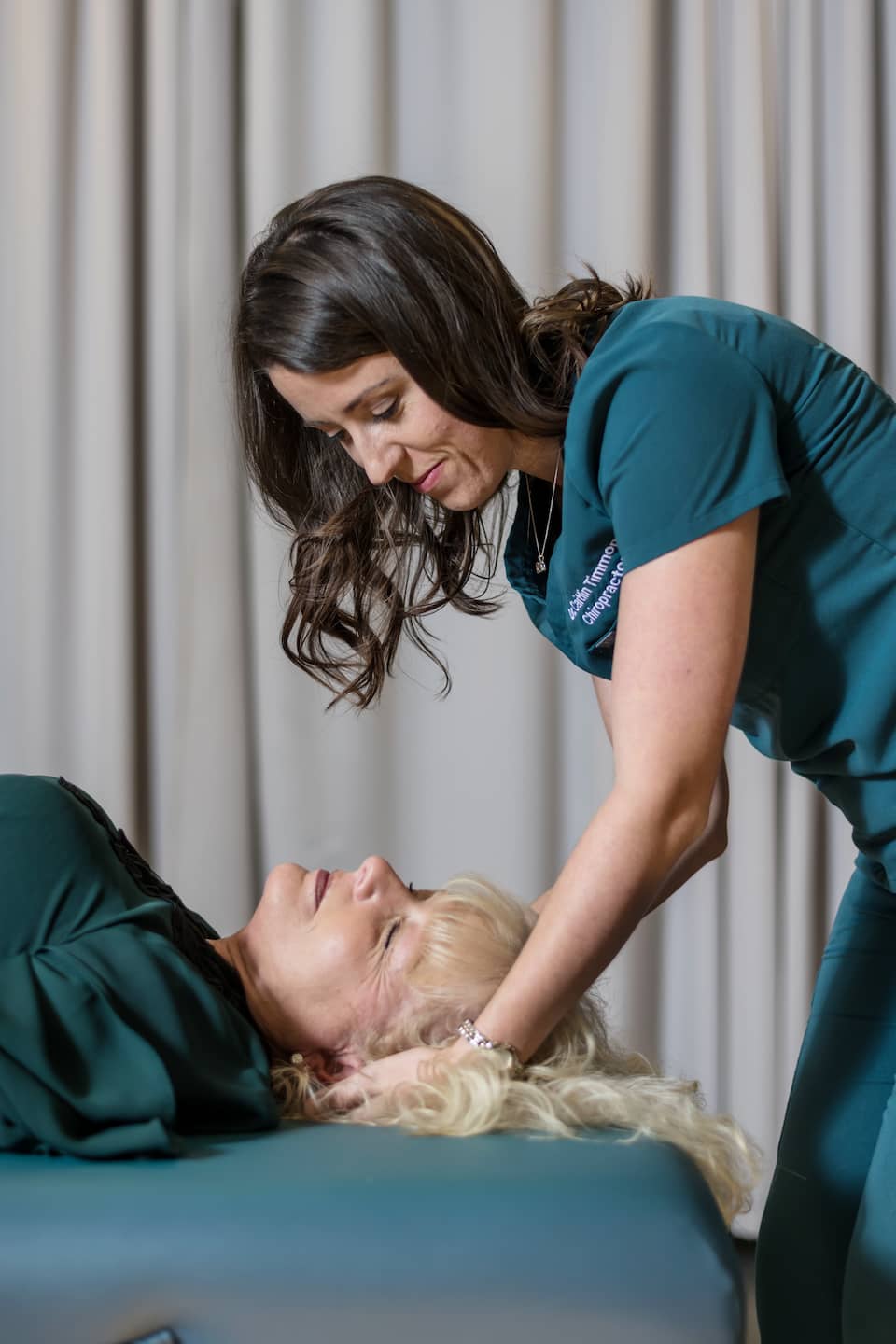 A woman is having a chiropractic adjustment with a chiropractor
